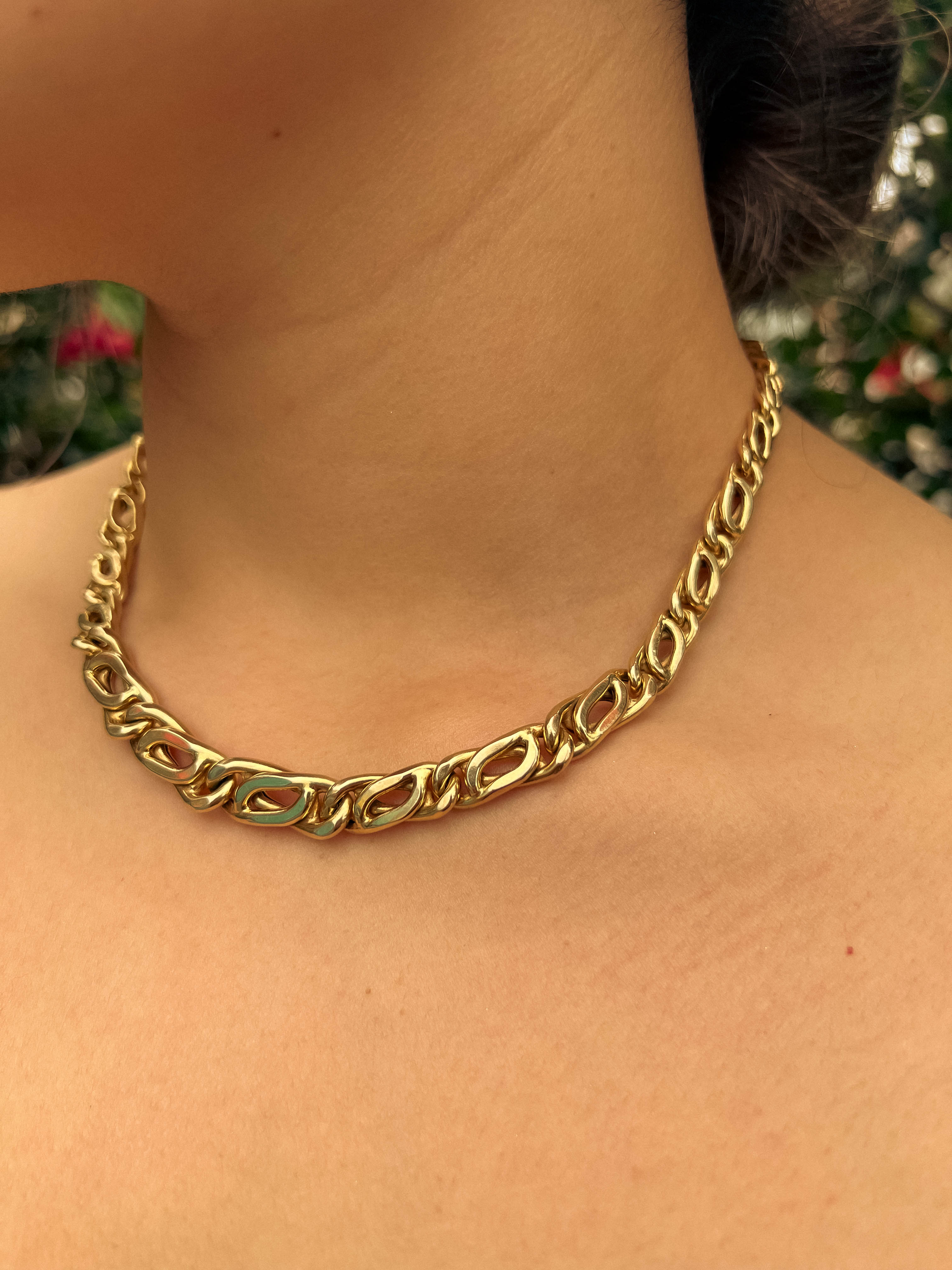 Woman wearing a chunky gold chain necklace around her neck.