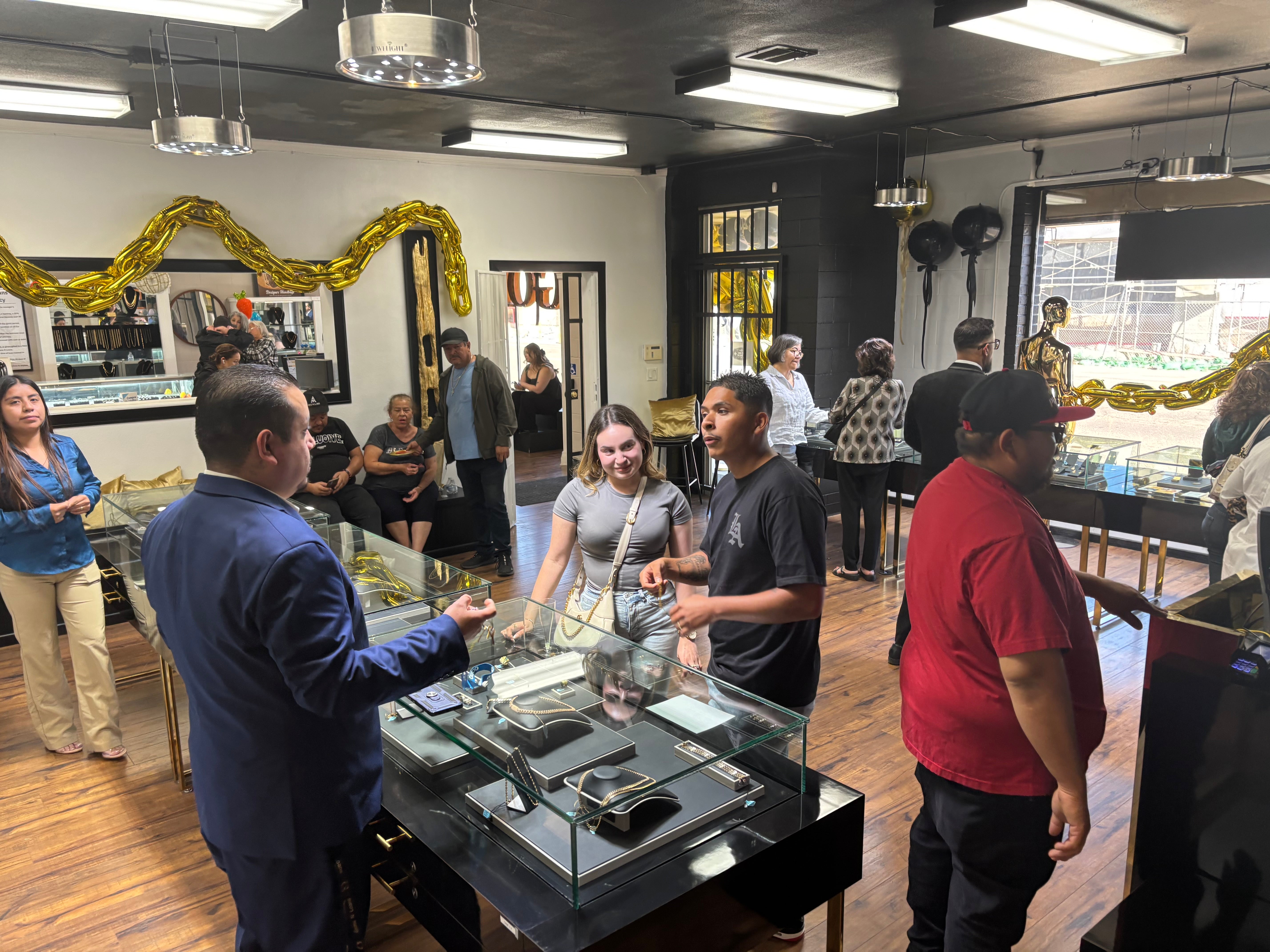 Customers browsing and interacting inside a jewelry store during a busy event, with staff assisting and display cases filled with jewelry.
